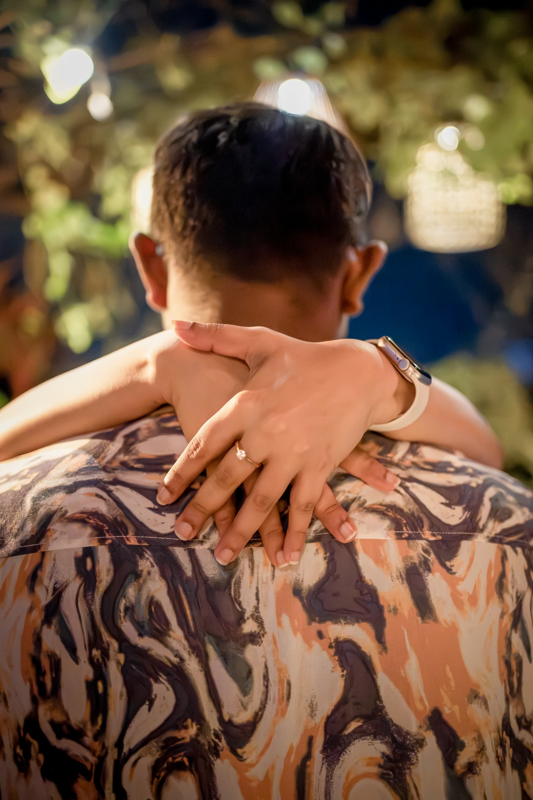 Sansani's hand, wearing her engagement ring, resting on Sachithra's shoulder